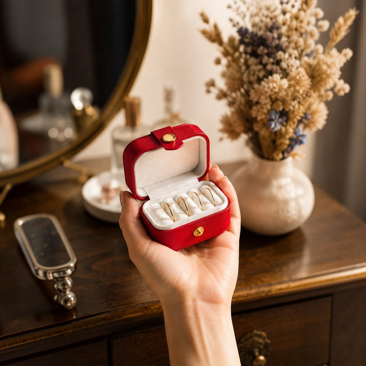 Boîte à bagues de voyage rouge ouverte tenue dans une main, format mini qui tient dans la paume