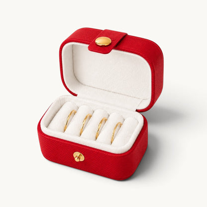 Boîte à bagues de voyage rouge ouverte, quatre fentes en velours blanc garnies de bagues dorées