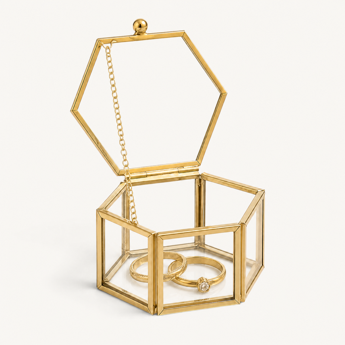 Boîte à bagues hexagonale ouverte avec bagues sur fond blanc cassé