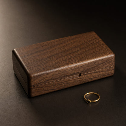 Boîte à bijoux en noyer fermée avec une bague dans une ambiance sombre