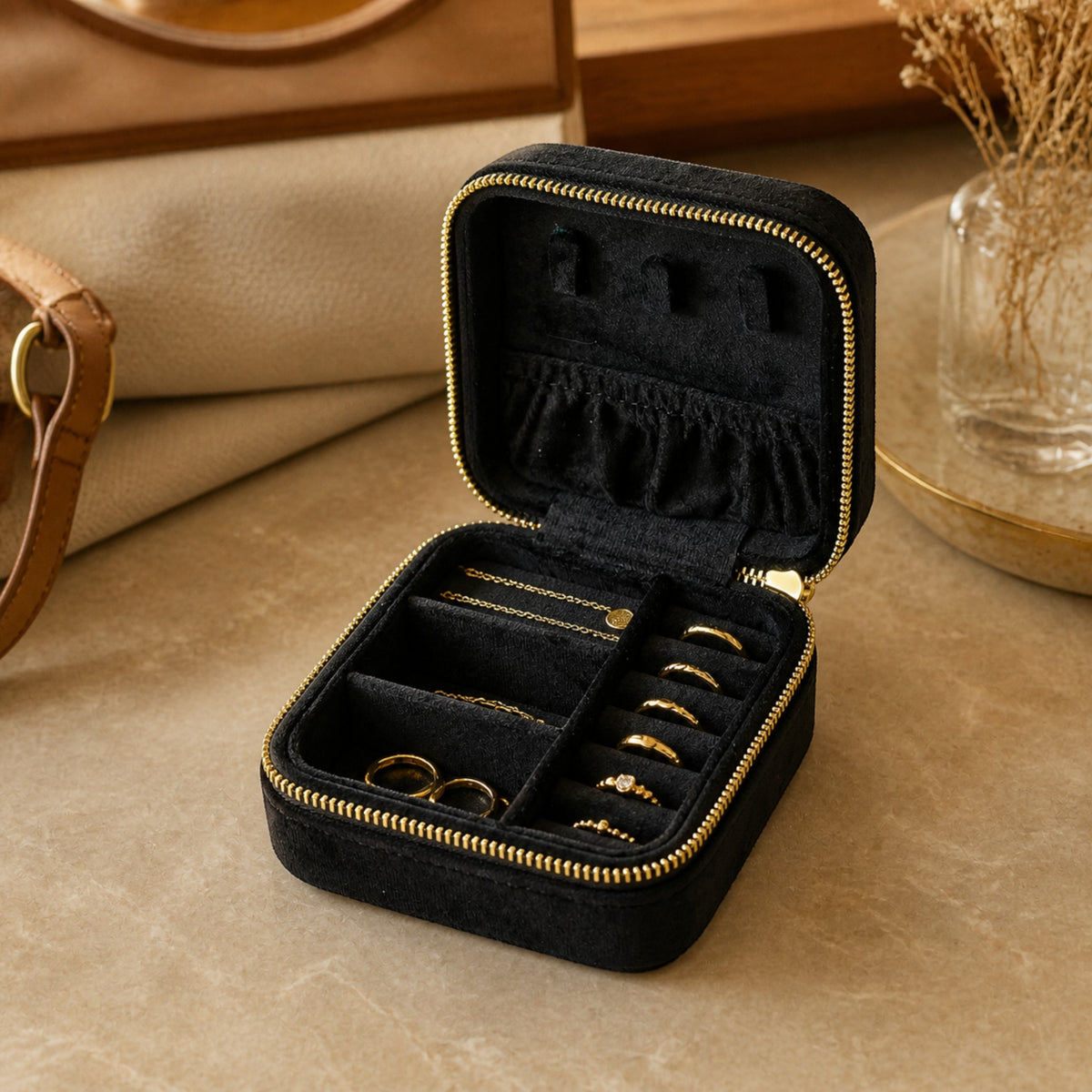 Boîte à bijoux de voyage en velours noir ouverte sur une coiffeuse d’hôtel