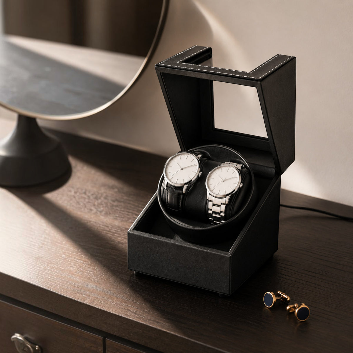 Remontoir double montre automatique noir posé sur une commode en bois, couvercle relevé et câble branché