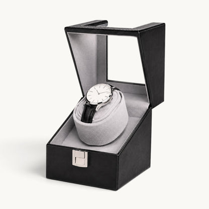 Remontoir montre automatique noir ouvert, couvercle relevé et coussin gris clair avec montre à bracelet cuir